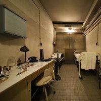 Kleines Arztzimmer im Operationsbunker Teichstraße mit Behandlungsliege, Schreibtisch und Telefon.